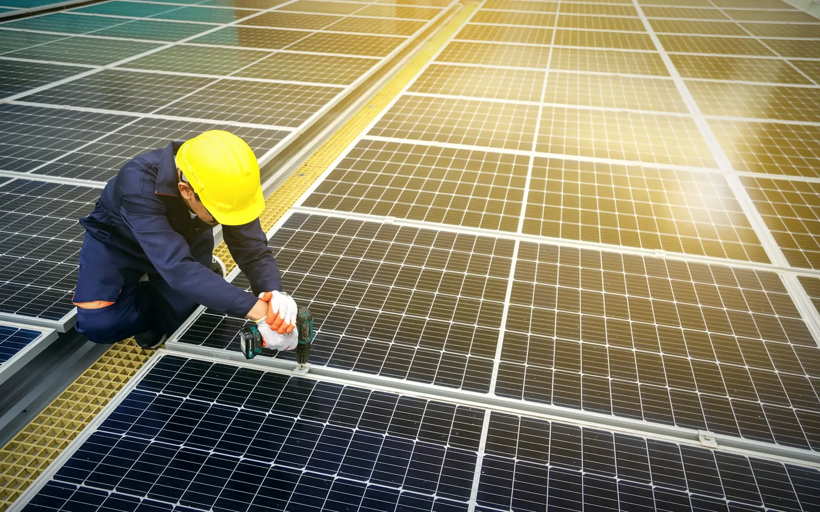 Engineer in a hard hat servicing a solar panel array