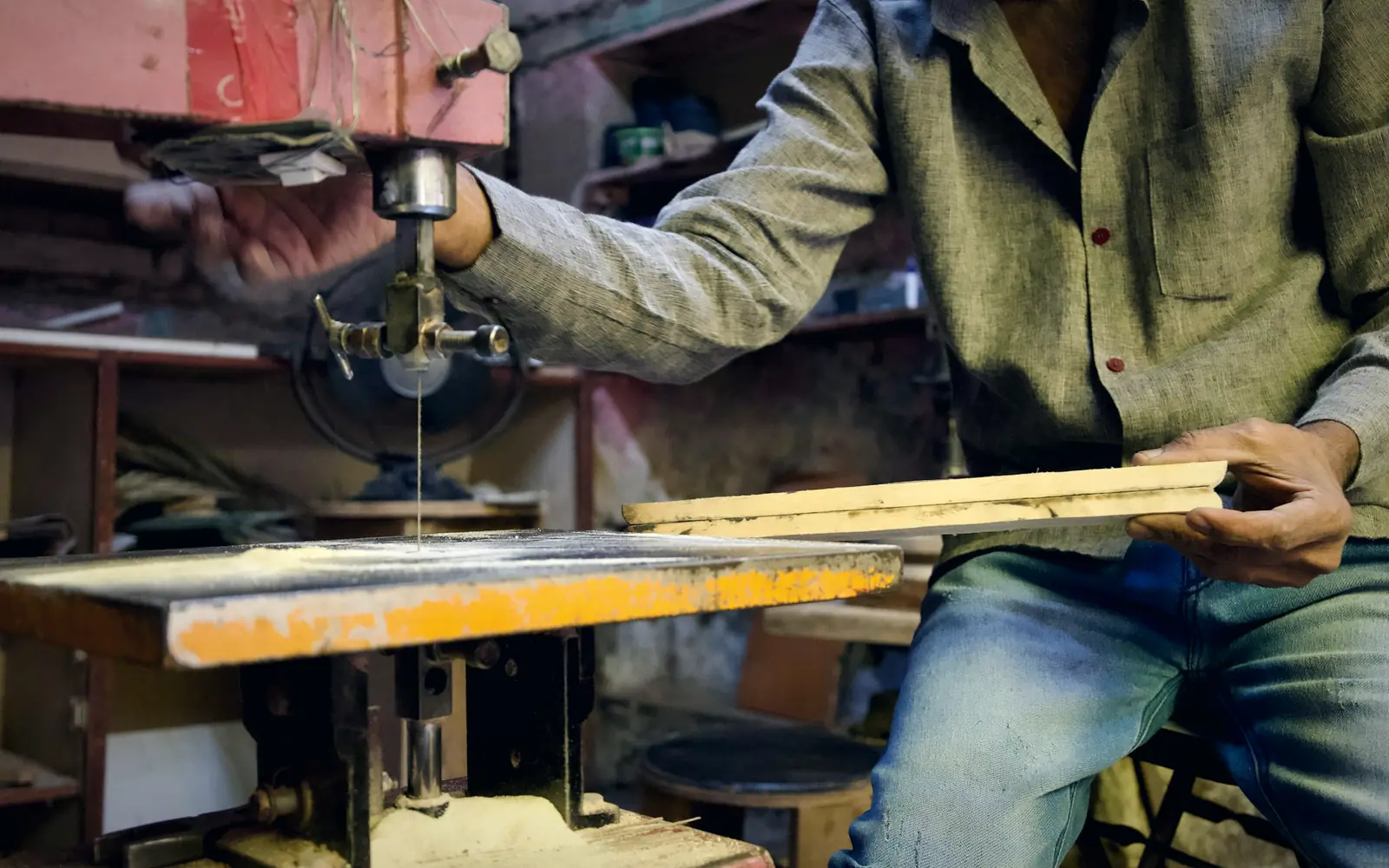 Carpenter cutting timber on a saw in a small workshop